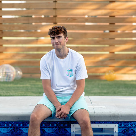 senior boy sits on edge of pool
