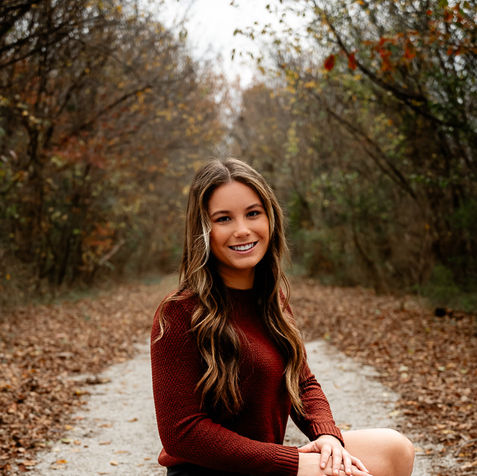 senior girl poses for fall photo shoot in the woods