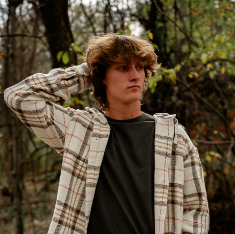 senior boy looks away from camera with hand in hair for his photos