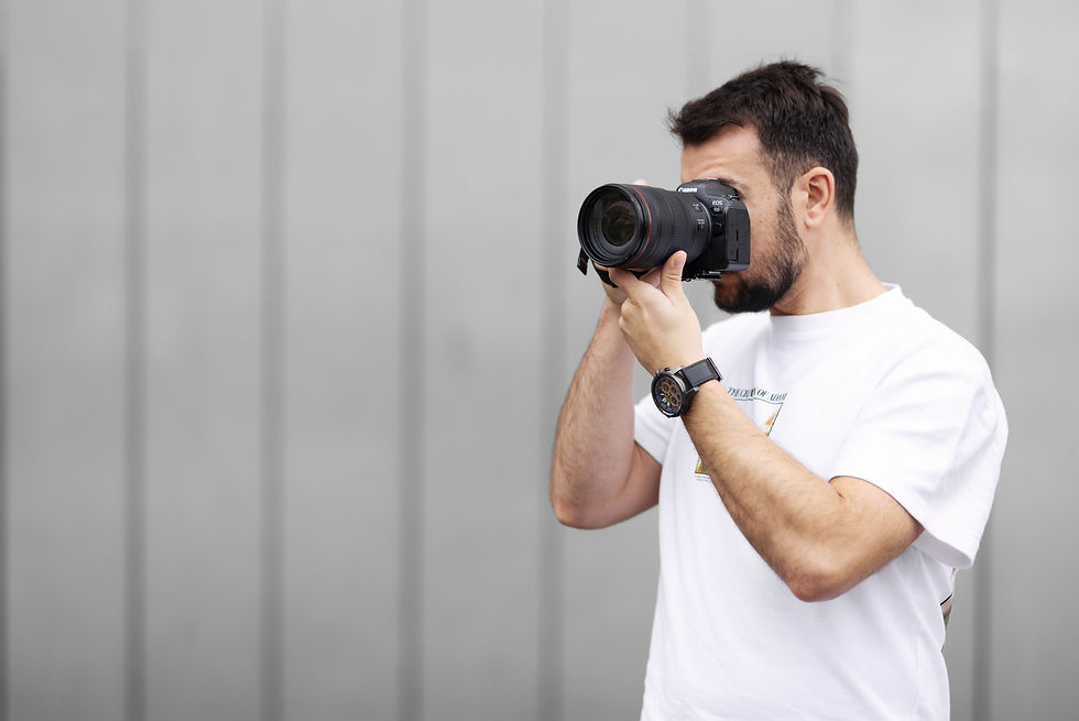 Male Birmingham professional photographer holding a camera to his eye, capturing photos in action.