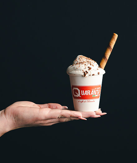 commercial image of a hand holding a small paper cup filled with ice cream