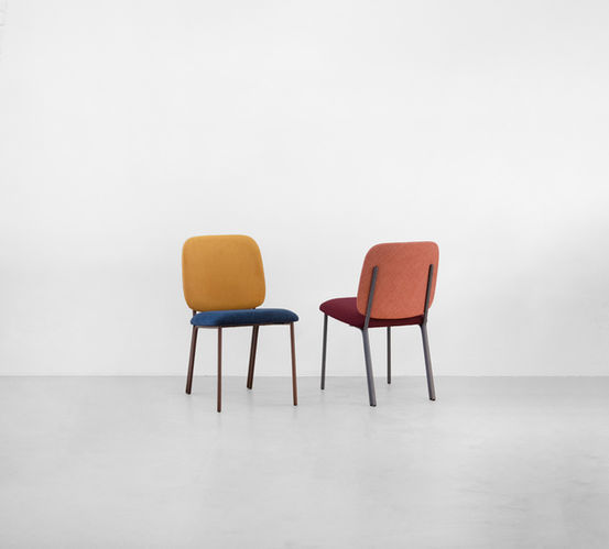 Duas Cadeiras Madalena totalmente estofadas: uma com encosto amarelo e assento azul, outra em coral e vinho