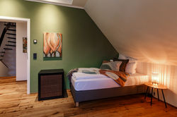 Einzelbett unter einer Dachschräge und an einer grünen Wand
