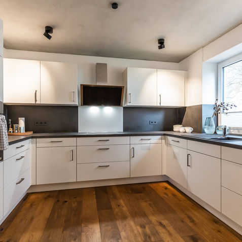 Eine weiße Küche in U-Form mit schwarzer Arbeitsplatte.