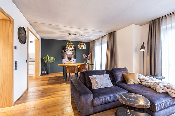 Esstisch aus Eiche mit vier gepolsterten Stühlen. Darüber zwei Lampen aus goldenem Metall.