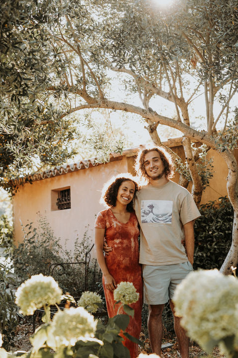 Idées tenues famille séance photo extérieur golden hour : robe jaune moutarde, chemise rouille, cardigan crème, robe enfant terracotta, pantalon kaki, body bébé beige, accessoires chapeau et sandales en tons chauds.