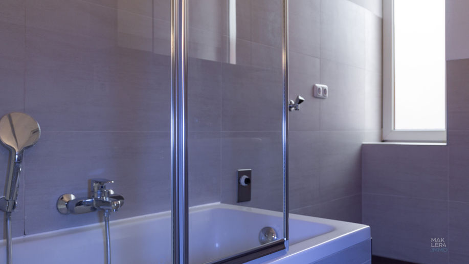 Badezimmer mit Badewanne, Glasabtrennung und Fenster in einer Wohnung in Schweinfurt
