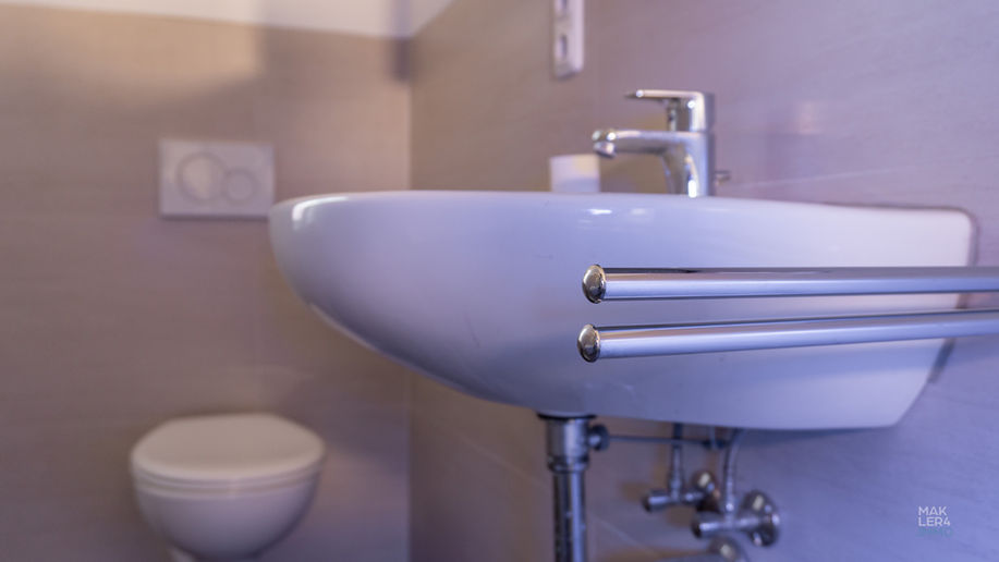 Waschbecken mit Handtuchhalter und WC in einem Badezimmer einer Wohnung in Schweinfurt