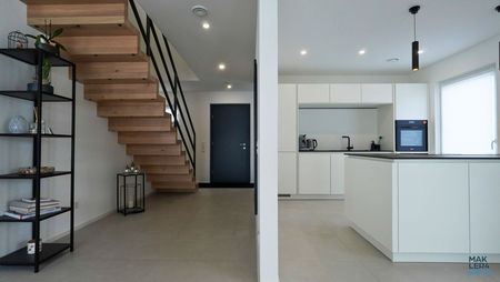 Eingangsbereich mit offener Holztreppe und moderner Küche im Hintergrund