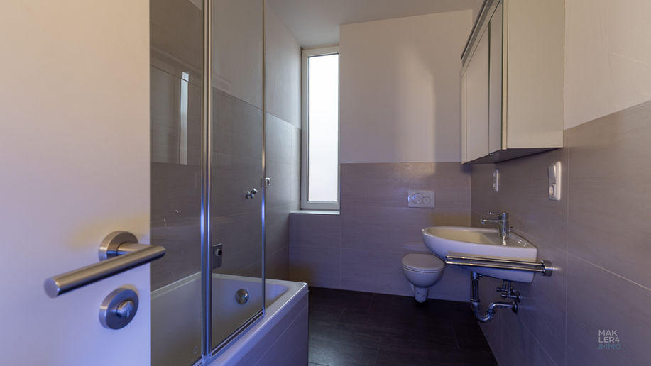 Badezimmer mit Badewanne, Glas-Duschabtrennung, Waschbecken und WC in einer Wohnung in Schweinfurt