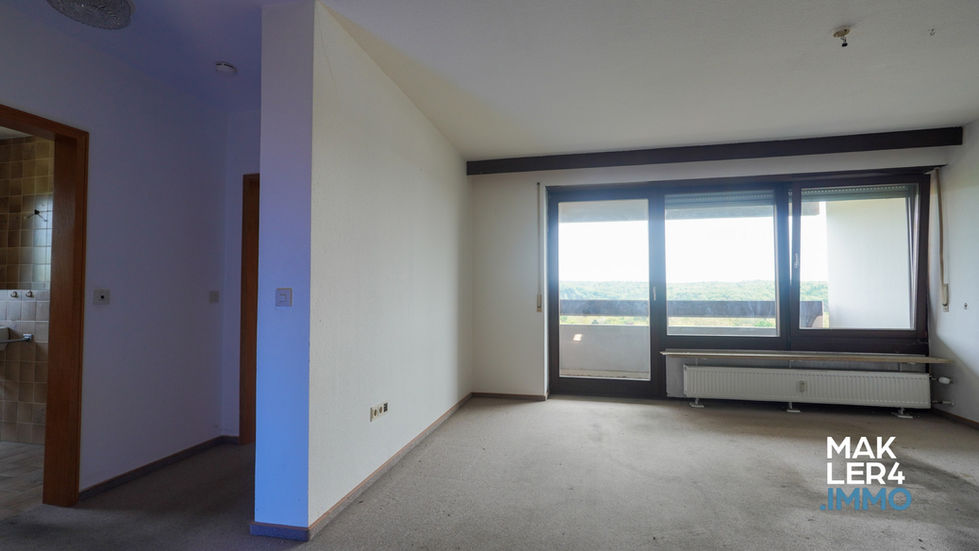 Wohnzimmer mit Balkonzugang, natürlichem Licht und angrenzendem Flur, Logo von MAKLER4.IMMO unten rechts platziert.