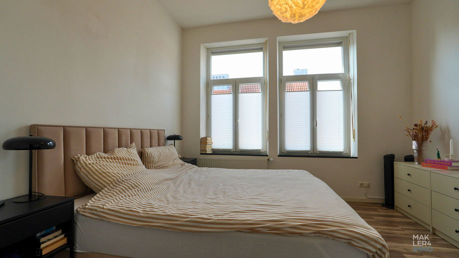 Schlafzimmer mit Doppelbett und großen Fenstern