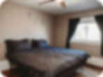 Bedroom with gray bedding, ceiling fan, and window at Huron Haus in Alpena.