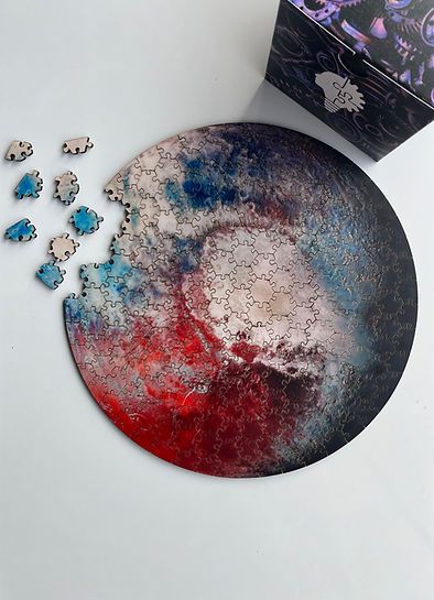 Round CircZle puzzle with red, blue, white abstract swirl, partly assembled with scattered pieces nearby.