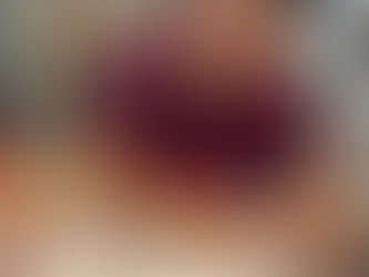 Man in glasses and burgundy shirt focused on assembling a circular puzzle on a white table. Indoors, with rustic decor in the background.