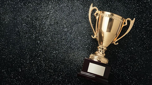 Golden trophy cup with handles placed on a dark glittery background, symbolizing achievement and victory.