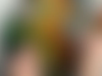 Hands assembling a vibrant, round puzzle of a tree with green and orange hues on a wooden table. Box with text partially visible.