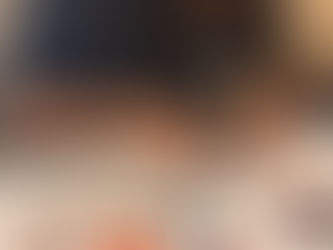 Man assembling a colorful puzzle at a table. Wearing a black shirt with white text. Wall in the background with a safety sign.