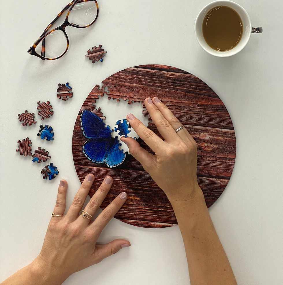 Hands completing butterfly puzzle on round wooden board with glasses and coffee Cogzart