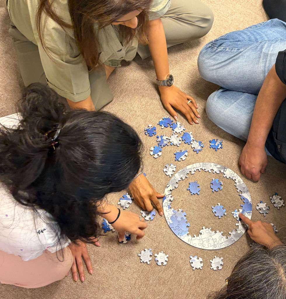 Four people assembling a blue and gray jigsaw puzzle on a beige carpet, focusing on completing a circular section.