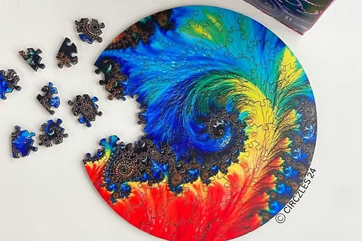 Colorful circular jigsaw puzzle with pieces missing and scattered on a white table; blue-green-red swirl pattern, Circles24 text.