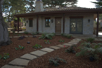 Stone veneer guest cottage behind a flagstone stepping-stone path laid in bark mulch