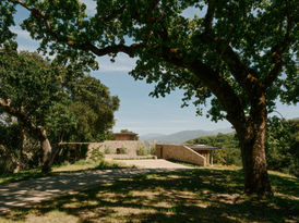 Oak-framed arrival court with stone walls stepping down toward distant mountain ridges