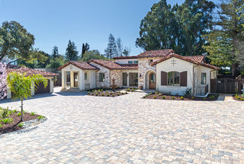 Wide paver motor court fronting a tile-roof home accented in Gold Limestone thin veneer