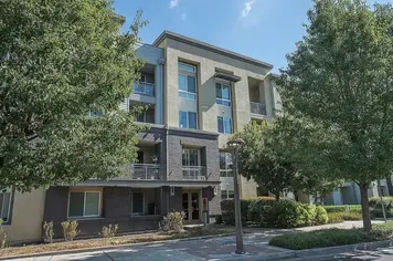Shaded sidewalk elevation with brick-faced lower units, balconies and stucco floors above