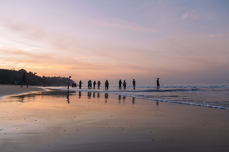 young people enjoying themselves at the seashore during an evening sunset.