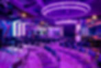 Eventlocation-Überblick mit lila Neon-Beleuchtung und Sitzreihen.