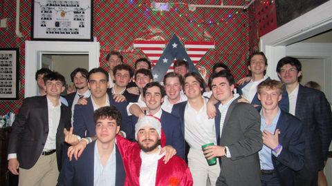 Group of men pose in front of Christmas decorations and an American star.