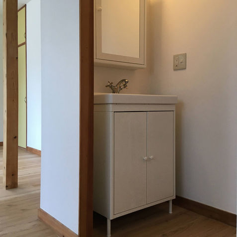 キッチン側から撮影した洗面スペースの写真。洗面キャビネットとミラーキャビネットが写り込む。