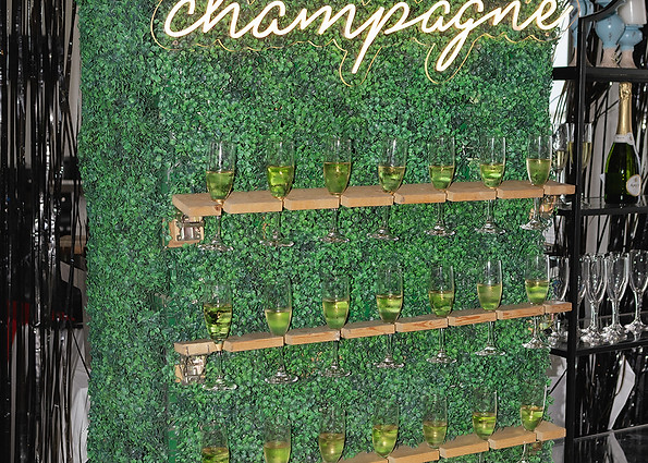 Luxury champagne wall featuring custom greenery, illuminated signage, and sparkling wine at a speakeasy-inspired 30th birthday celebration.