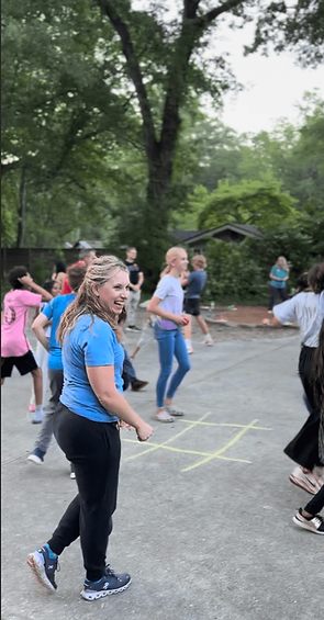 a woman laughs while other people move around her during a summer mentoring group facilitated by Resilient Communities Center staff