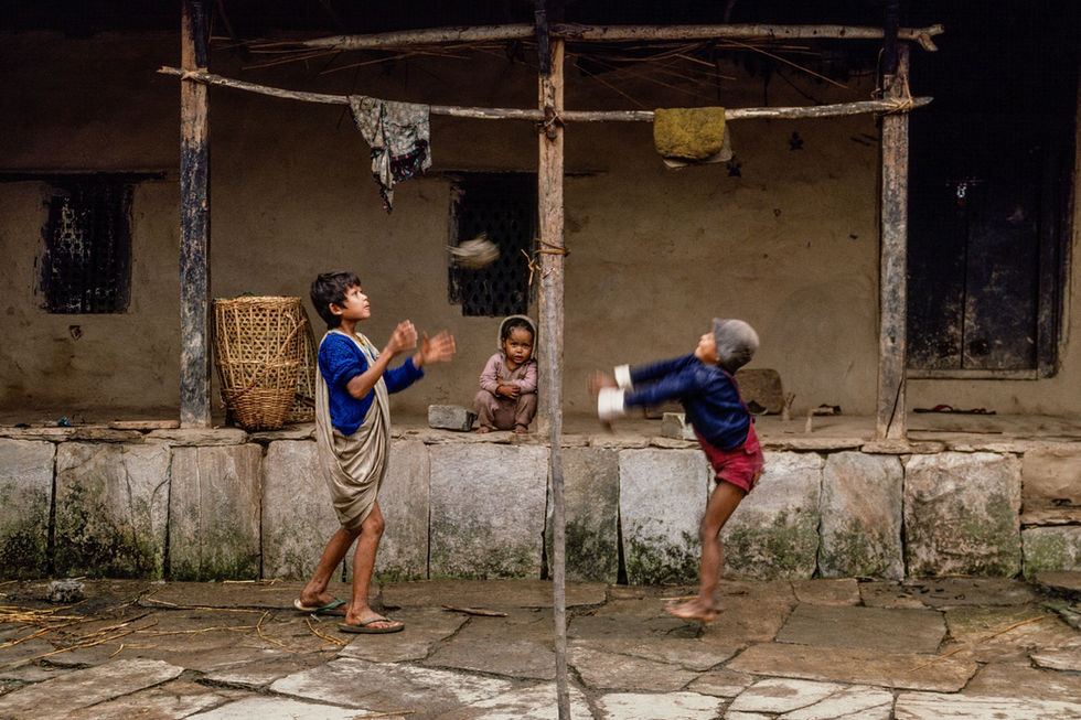 Playing ball over a string in front of a farmhouse in Ghandruk in the southern Annapurna region. Nepal, 1990.
