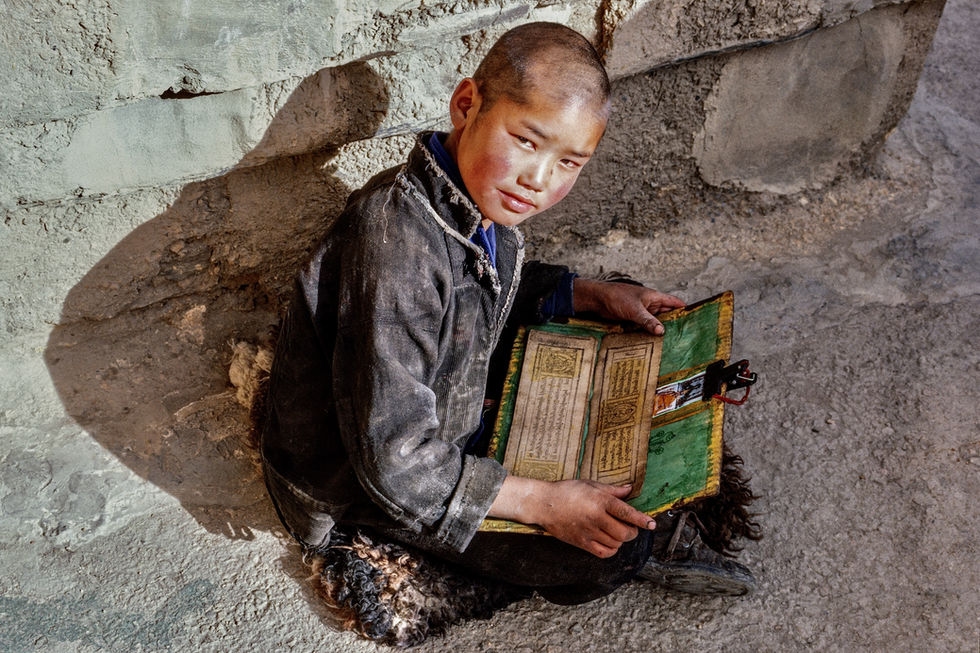 A boy studies a Buddhist text to become a novice at Pelkhor Chode Monastery in Gyantse. Tibet, 1987.