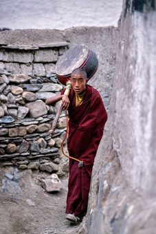 A monk with a drum walks to his monastery in the small town of Shelkar in the Tingri region. Tibet, 1999.