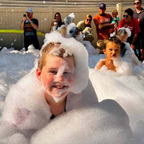 Kids laughing while playing in fluffy foam at a summer birthday party