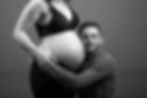 Portrait en noir et blanc d’un homme enlacé contre le ventre de sa compagne enceinte