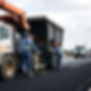 Workers working on asphalt with machine, trucks (North America).jpg