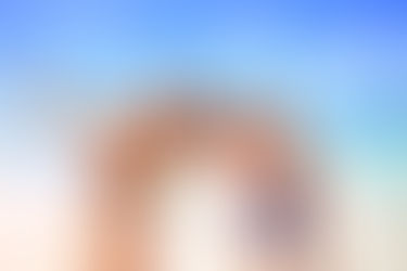 Happy family of four at a sunny beach near the ocean.