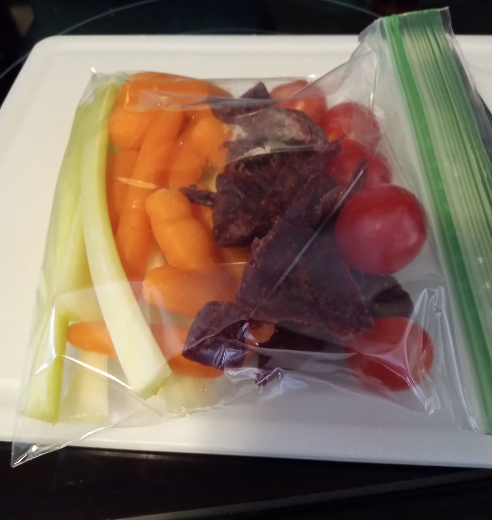 A zip-lock bag with carrots, celery, cherry tomatoes, and beef jerky on a white cutting board. (Vibrant Colors)