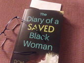 Picture of the book, The Diary of a Saved Black Woman, on a cushion with a pair of reading glasses laid to the side.