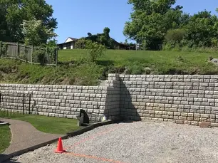Segmental concrete block retaining wall on hilly Western PA residential property showing professional installation with proper drainage