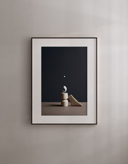 Solstizio in a black frame with a white mount, displayed on a pale wall.