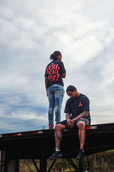 Two men on trailer, one standing, "YOU CAN DO IT " t-shirt.