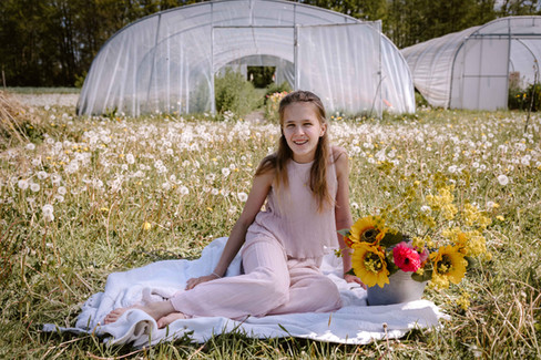 tienermeisje in een roze outfit, tijdens een lentefeest fotosessie in de bloemenpluktuin De Bloemekeet in Herselt, zittend tussen de bloemen buiten