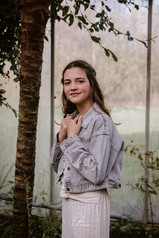 tiener in een beige outfit, tijdens haar communieshoot in de canna banana in putte, vestje vasthoudend