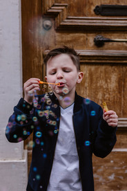 Jongen tijdens een fotoshoot voor zijn communiefoto's in het Begijnhof in Lier, bellen aan het blazen